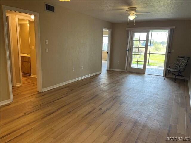 spare room featuring ceiling fan with notable chandelier and light wood-type flooring