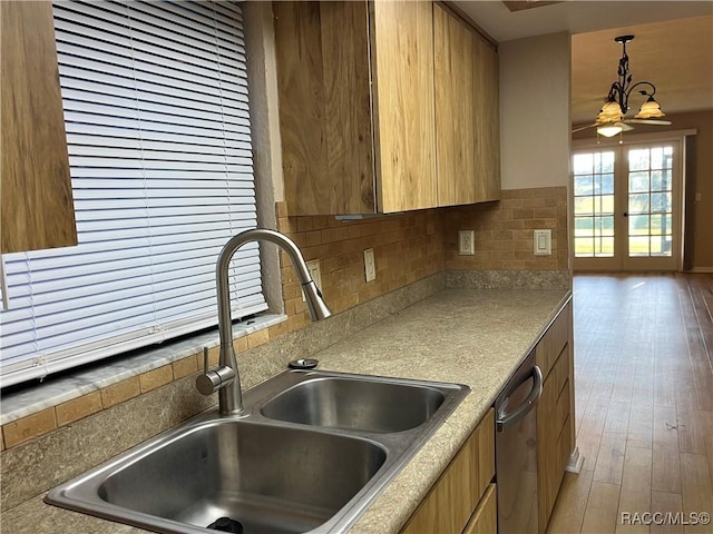 kitchen featuring decorative backsplash, stainless steel dishwasher, ceiling fan, sink, and hardwood / wood-style flooring