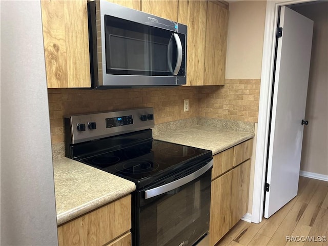 kitchen with appliances with stainless steel finishes, tasteful backsplash, and light hardwood / wood-style flooring