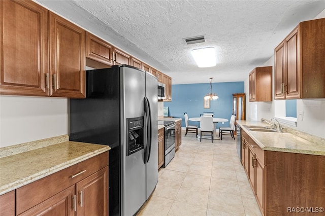 kitchen featuring appliances with stainless steel finishes, a textured ceiling, sink, an inviting chandelier, and hanging light fixtures