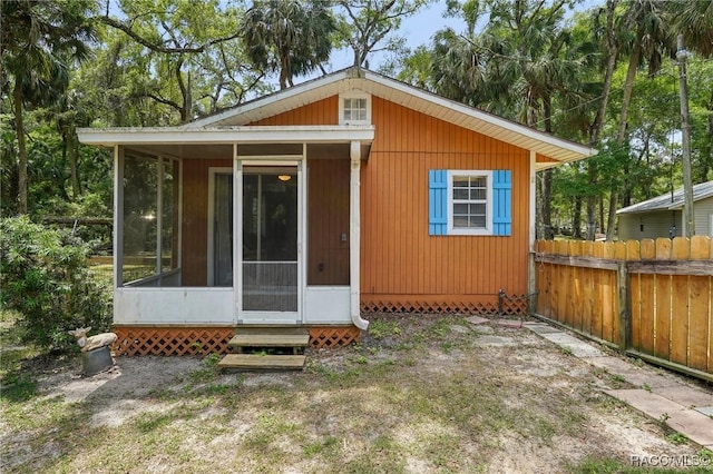 back of property with a sunroom, fence, and entry steps