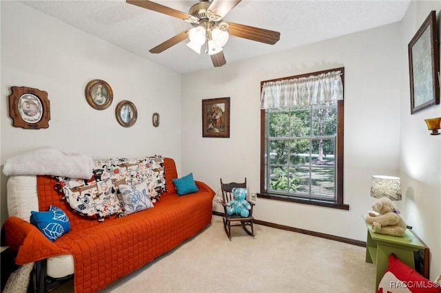 carpeted living area with baseboards and ceiling fan