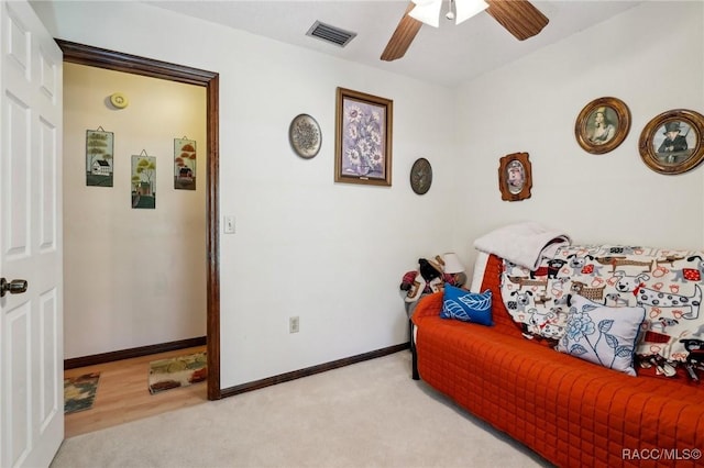 interior space featuring visible vents, baseboards, ceiling fan, and light carpet