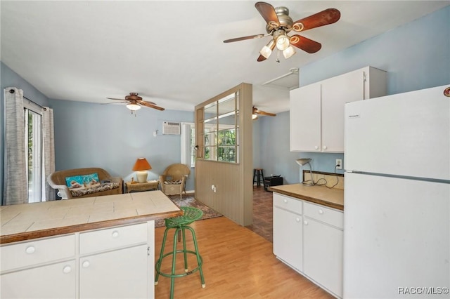 kitchen with freestanding refrigerator, ceiling fan, a healthy amount of sunlight, and white cabinets