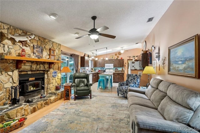 living area with visible vents, lofted ceiling, light wood-style floors, a textured ceiling, and a ceiling fan
