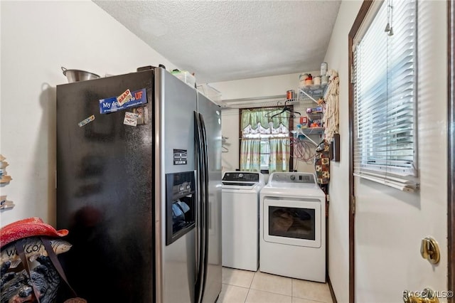 clothes washing area with laundry area, plenty of natural light, a textured ceiling, independent washer and dryer, and light tile patterned floors