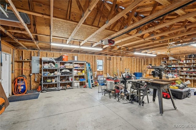 garage with a garage door opener, electric panel, and a workshop area