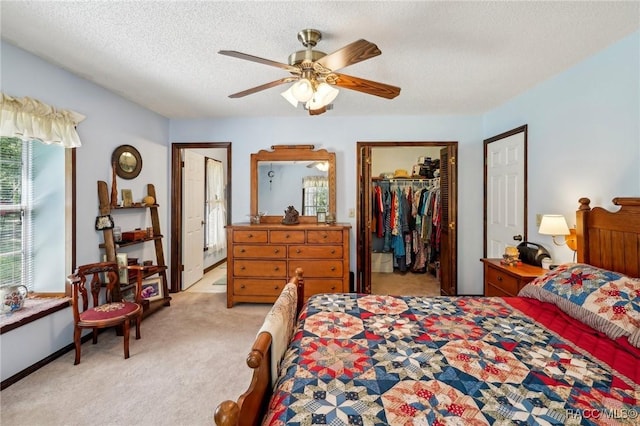 bedroom featuring ceiling fan, light colored carpet, a textured ceiling, a spacious closet, and a closet
