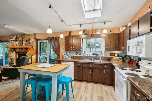 kitchen featuring dark brown cabinets, white appliances, light wood-type flooring, a textured ceiling, and a sink