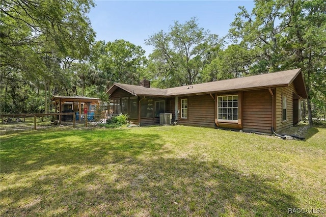 back of property with a yard, central AC, a chimney, and a sunroom