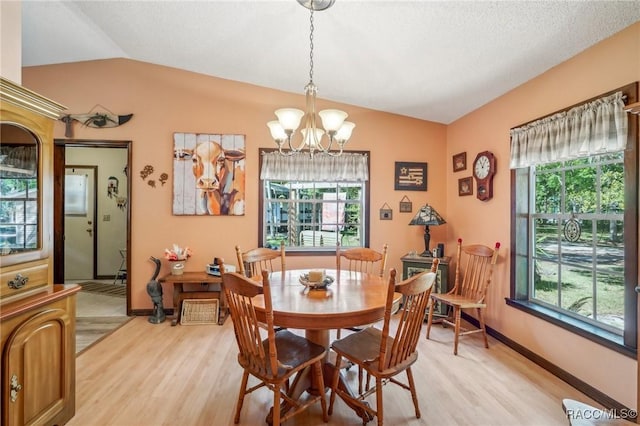 dining area with baseboards, a chandelier, lofted ceiling, and light wood-type flooring