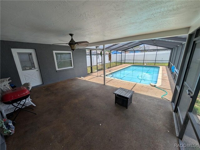 view of swimming pool with a patio, a ceiling fan, a lanai, and fence