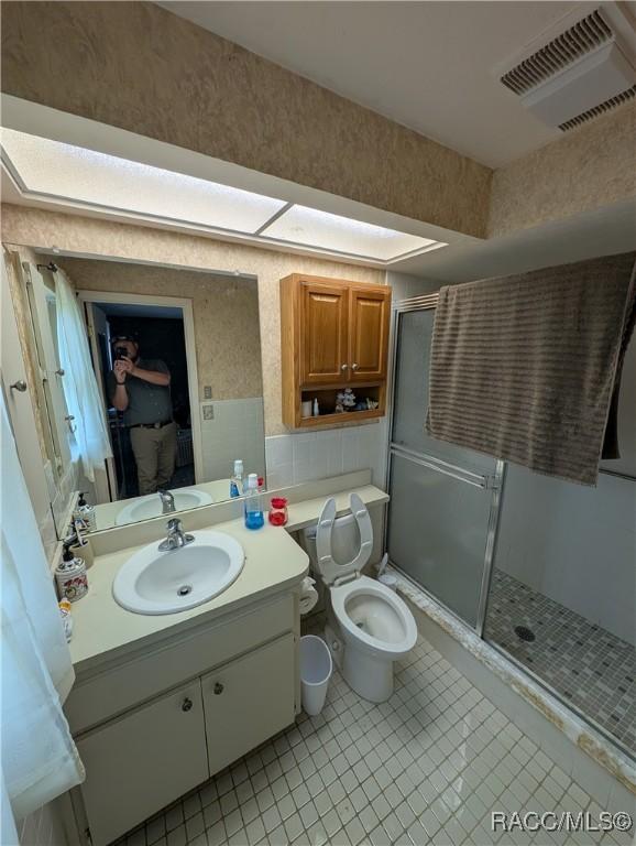 full bathroom with a stall shower, vanity, tile patterned floors, and toilet