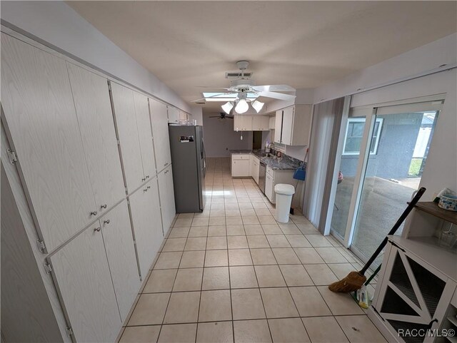 kitchen with appliances with stainless steel finishes, a ceiling fan, light tile patterned floors, a sink, and white cabinets