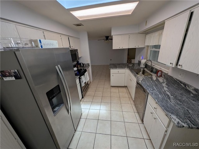kitchen featuring appliances with stainless steel finishes, a sink, light tile patterned flooring, white cabinets, and a ceiling fan