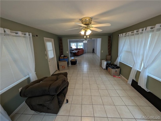 unfurnished living room with light tile patterned floors, a ceiling fan, and baseboards