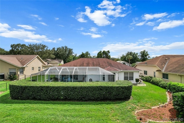 back of property with a lawn, central AC unit, and a lanai