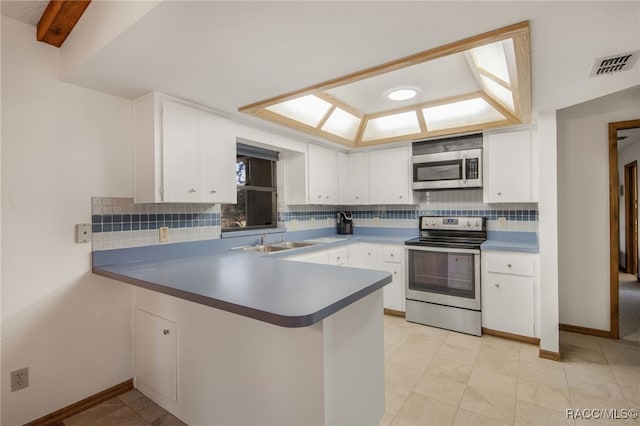 kitchen with white cabinets, stainless steel appliances, decorative backsplash, sink, and kitchen peninsula