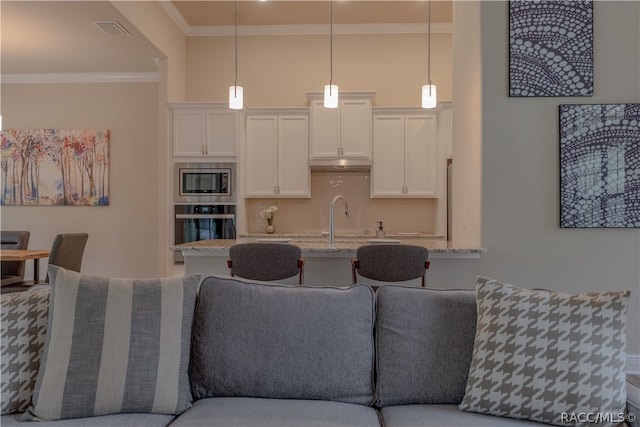 kitchen featuring sink, hanging light fixtures, appliances with stainless steel finishes, light stone counters, and white cabinetry