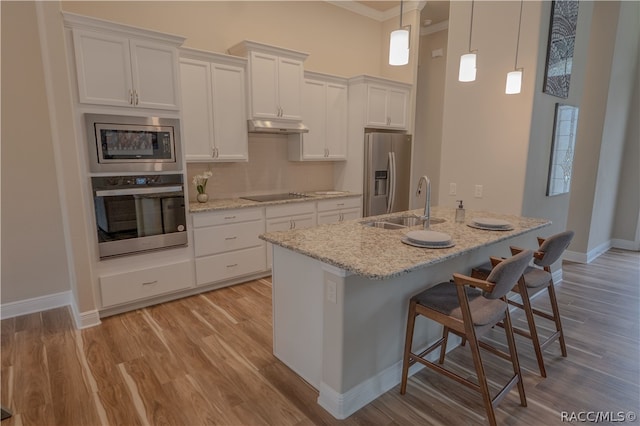 kitchen with crown molding, hanging light fixtures, light stone countertops, white cabinetry, and stainless steel appliances