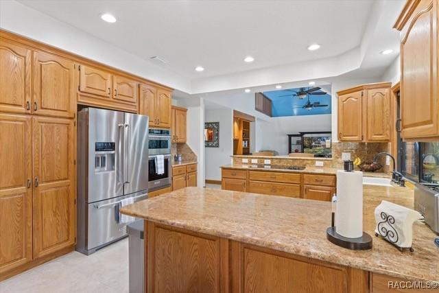 kitchen with light stone counters, appliances with stainless steel finishes, kitchen peninsula, and tasteful backsplash