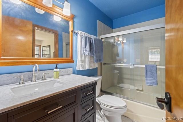 full bathroom featuring vanity, toilet, and combined bath / shower with glass door