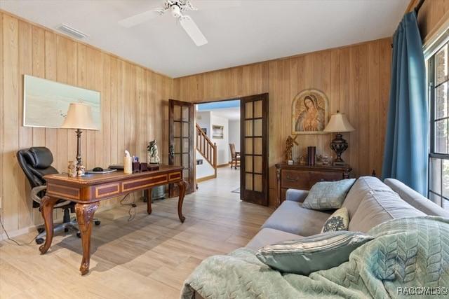 home office featuring french doors, ceiling fan, and wooden walls