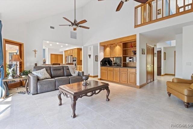 living room with built in shelves, high vaulted ceiling, and ceiling fan