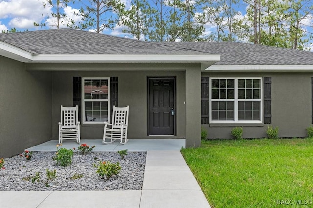 977 W Homeway Loop, Citrus Springs, FL 34434 - doorway to property featuring a porch, a shingled roof, stucco siding, and a lawn