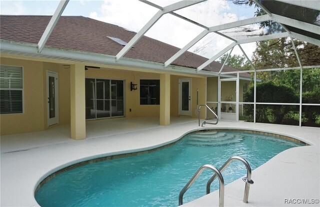 view of swimming pool featuring glass enclosure and a patio