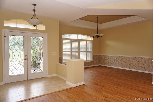 entryway with hardwood / wood-style floors, a notable chandelier, french doors, and a tray ceiling