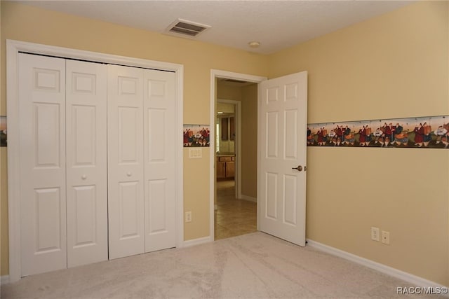 unfurnished bedroom featuring a closet and light colored carpet