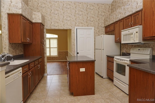 kitchen with light tile patterned flooring, white appliances, a center island, and sink