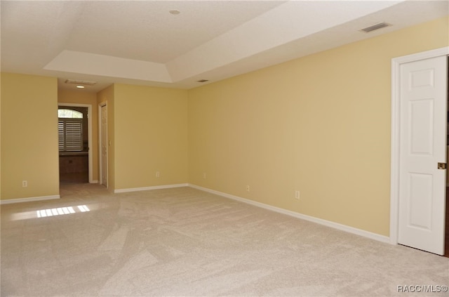 unfurnished room featuring a tray ceiling and light carpet