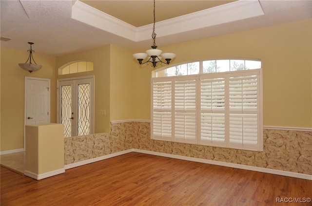 interior space featuring a raised ceiling, an inviting chandelier, a textured ceiling, and hardwood / wood-style flooring