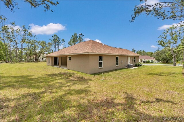 5443 N Nakoma Dr, Beverly Hills, FL 34465 - rear view of house featuring stucco siding and a lawn