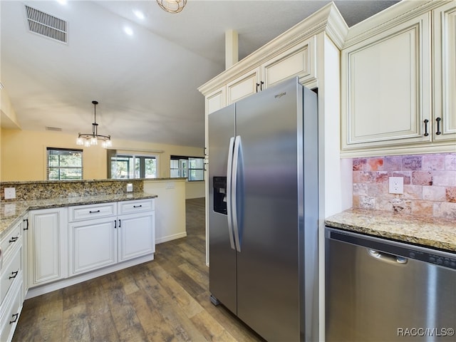 kitchen featuring lofted ceiling, light stone countertops, appliances with stainless steel finishes, decorative light fixtures, and dark hardwood / wood-style flooring