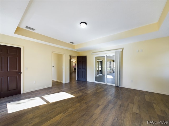 spare room featuring dark hardwood / wood-style flooring and a tray ceiling