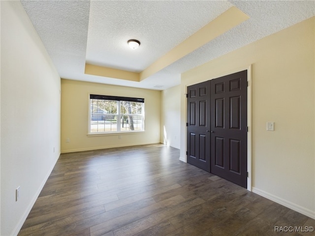 foyer entrance with a textured ceiling, a raised ceiling, and dark hardwood / wood-style floors