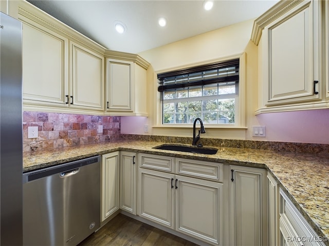 kitchen with appliances with stainless steel finishes, dark hardwood / wood-style flooring, sink, stone countertops, and cream cabinetry