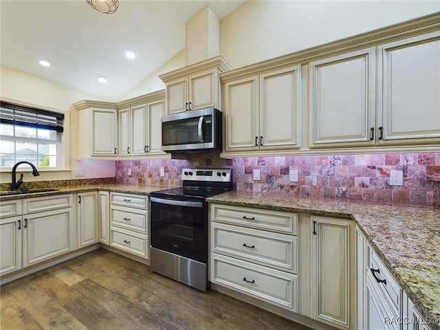 kitchen with dark hardwood / wood-style flooring, stainless steel appliances, sink, cream cabinetry, and lofted ceiling