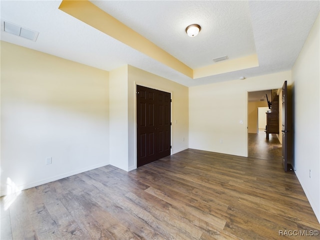 spare room with a textured ceiling and dark hardwood / wood-style floors