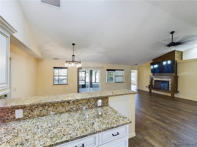 kitchen featuring dark hardwood / wood-style flooring, ceiling fan with notable chandelier, vaulted ceiling, white cabinets, and hanging light fixtures