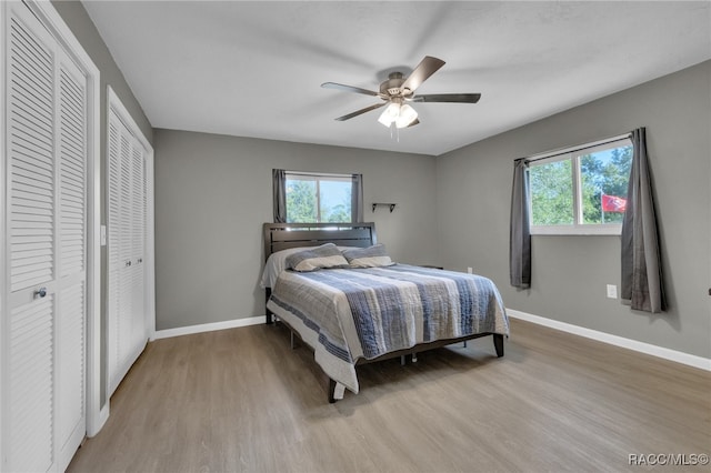 bedroom with multiple closets, ceiling fan, and light wood-type flooring