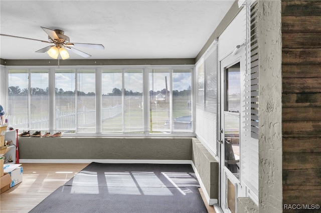 unfurnished sunroom with ceiling fan and plenty of natural light