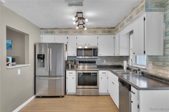 kitchen with white cabinets, appliances with stainless steel finishes, light hardwood / wood-style flooring, and sink