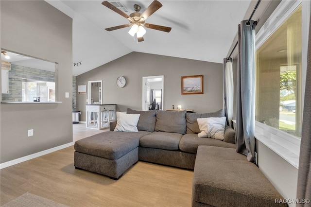 living room featuring a wealth of natural light, light hardwood / wood-style flooring, ceiling fan, and vaulted ceiling