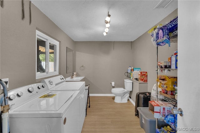 clothes washing area featuring washing machine and dryer, light wood-type flooring, and sink