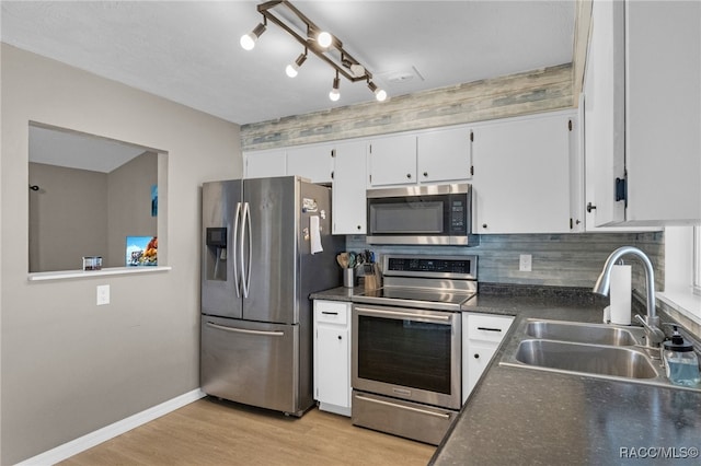 kitchen with backsplash, sink, light hardwood / wood-style flooring, appliances with stainless steel finishes, and white cabinetry