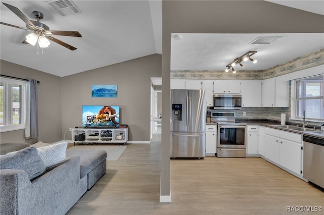 kitchen with lofted ceiling, white cabinets, sink, light wood-type flooring, and stainless steel appliances